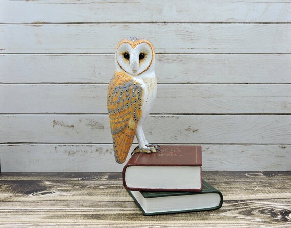 Barn owl on books, an owl sculpture.